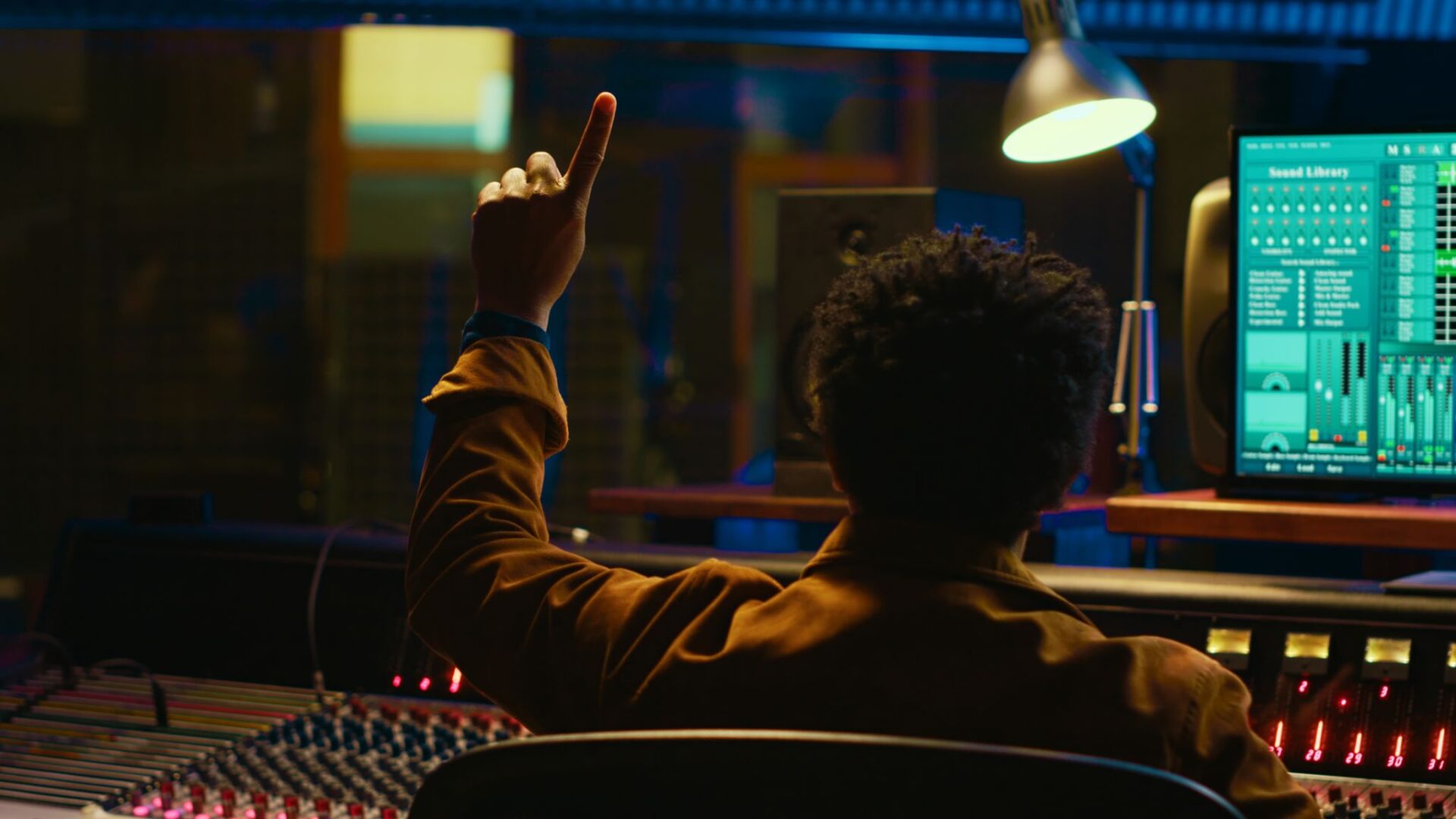 Person in studio pointing, surrounded by equipment.