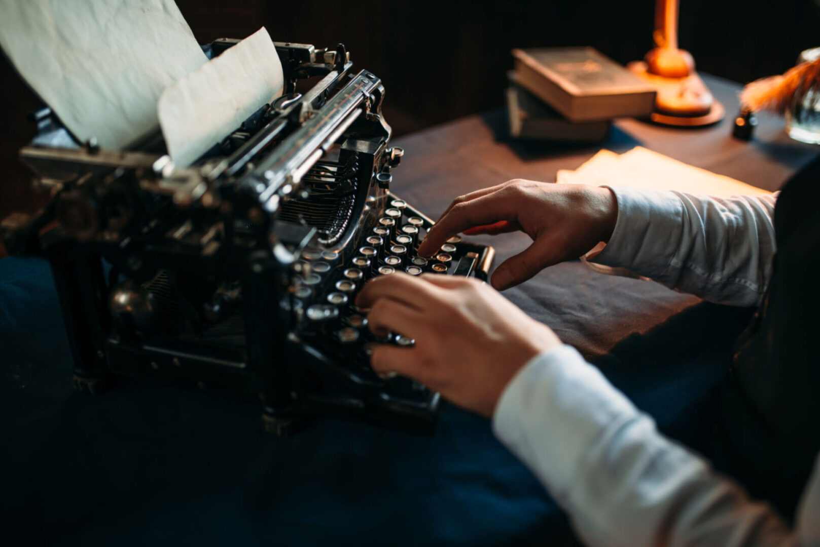 Person typing on vintage typewriter, dimly lit.