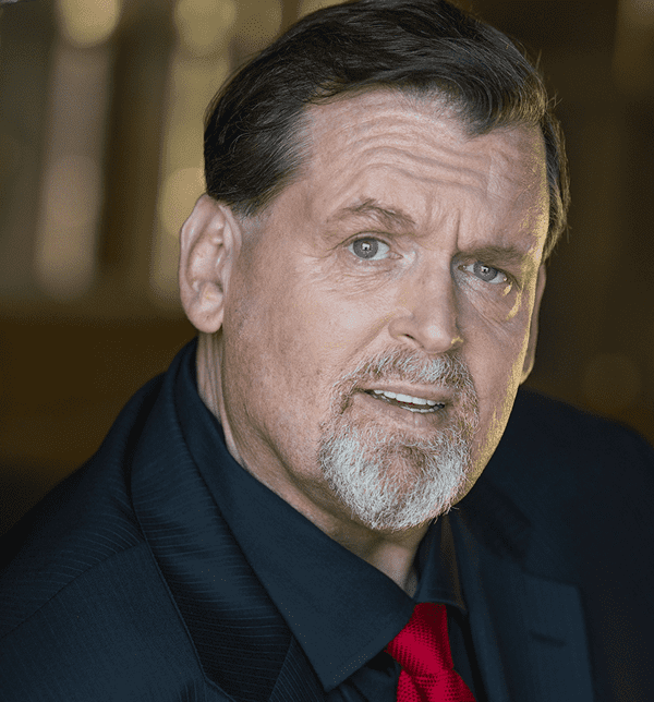 Portrait of a middle-aged man with a beard and mustache, wearing a dark suit and red tie.